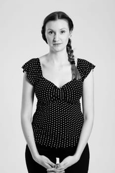 Black and white studio portrait of attractive woman with pigtail holding hands together