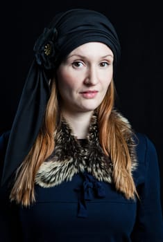 Studio portrait of stylish attractive woman wearing blue outfit and head scarf against dark background
