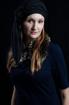 Studio portrait of stylish attractive woman wearing blue outfit and head scarf against dark background