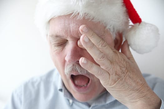 older man rubs his eye and yawns
