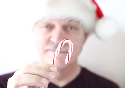 man in Santa hat offers a candy cane