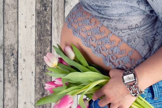 Baby belly with fresh tulips