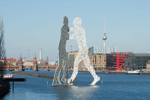 Molecule Men statue in front of the city silhouette of Berlin