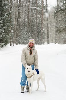 Woman with a dog on a walk in the woods during a snowfall