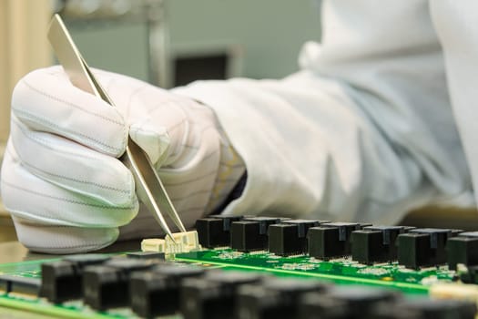 Female hand holding tweezers and installing connector on PCB in turnkey solutions high-tech manufacturing