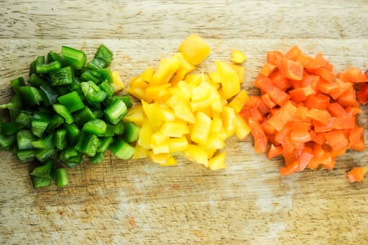 slices of colorful sweet bell pepper on wood board.