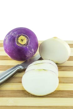 purple headed turnips with slices and knife on wood board.
