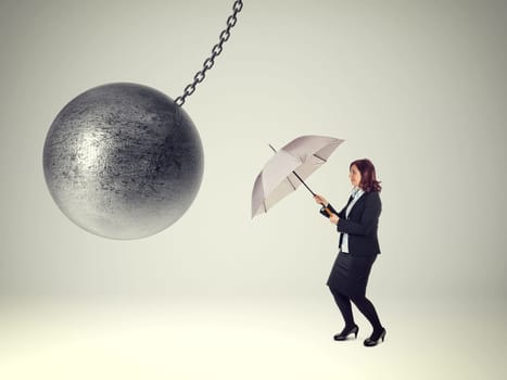 businesswoman with umbrella and heavy iron ball