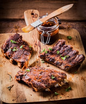 Three portions of spicy grilled ribs basted with a savory aromatic sauce and garnished with herbs for a delicious meal