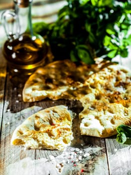 Eating Italian focaccia bread, a high gluten ovenbaked flatbread flavored with olive oil and herbs, served on a rustic wooden table