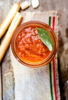 Grissini bread sticks with a glass jar of savory spicy tomato relish for a tasty Italian appetizer, overhead view with copyspace