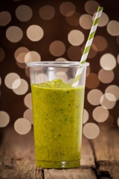 Healthy green vegetable smoothie with a blend of fresh vegetables against a bokeh of party lights