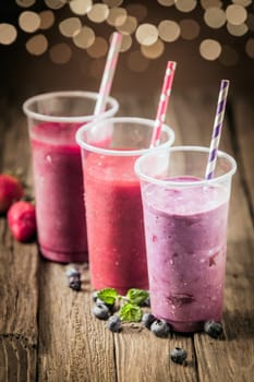 Berry smoothies with farm fresh blueberries and strawberries blended with yogurt and ice cream for a healthy summer treat with a bokeh of sparkling party lights