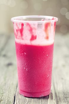 Drinking a fresh healthy chilled strawberry and yogurt smoothie with a partially consumed drink in a plastic glass