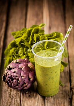 Healthy vegetarian artichoke and lettuce smoothie with fresh ingredients on an old rustic wooden kitchen table