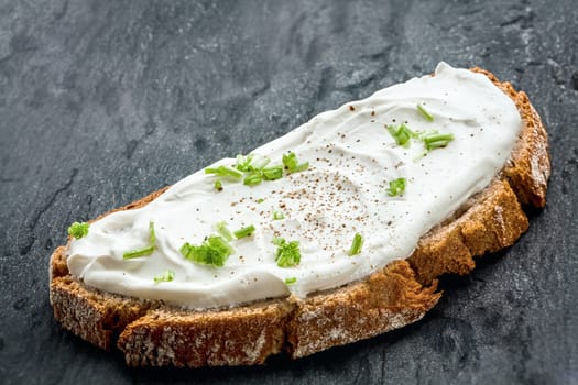 Healthy low fat cream cheese and chopped chives on a slice of freshly baked rye bread, close up low angle view