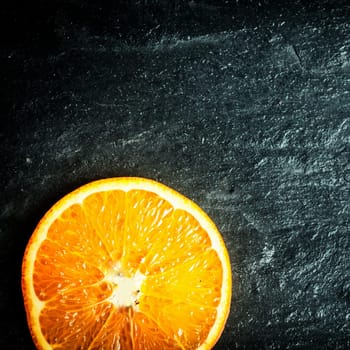 Colorful halved fresh juicy ripe orange on a dark texture wooden surface with copyspace, overhead view in square format