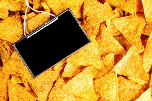 Background of golden crisp crunchy spicy corn tortillas or nachos with their ditsinctive triangular shape with a small blank vintage school slate for your text