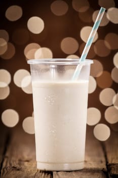 Creamy fruity smoothie on an old wooden bar counter against a festive brown bokeh of sparkling party lights at a summer celebration