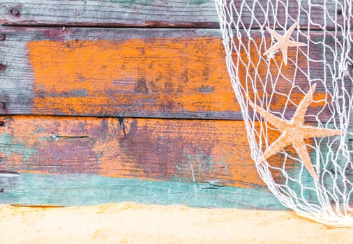 Nautical starfish background with rustic grunge weathered blue painted wooden boards, fishing net and golden beach sand, copyspace for text