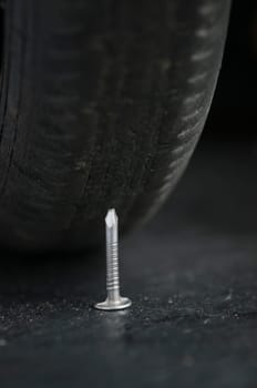 Close-up with low depth of field of a vehicle tire and a nail in front of it