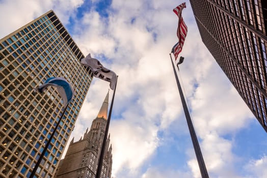 Looking up at buildings and flags in downtown Chicago