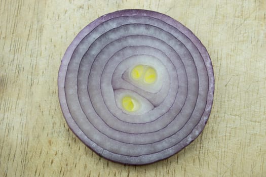 Red sliced onion on wooden kitchen board.