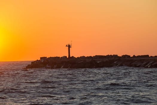 Morning dawn on the harbor pier beacon lights at the entrance into the open ocean seas