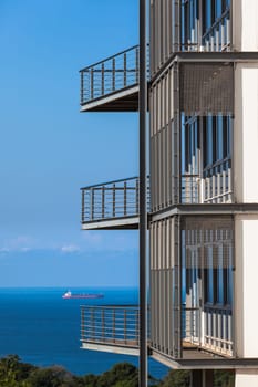 Building section of three porch verandahs overlooking blue ocean with distant ship