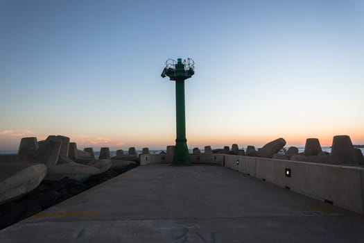 Morning dawn on the harbor pier beacon lights at the entrance into the open ocean seas