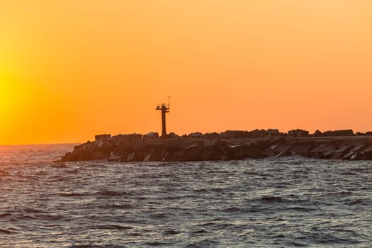 Morning dawn on the harbor pier beacon lights at the entrance into the open ocean seas