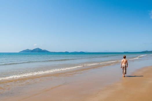 Boy in waters walking along tropical waters at  mission beach nearby Cairns Queensland Australia