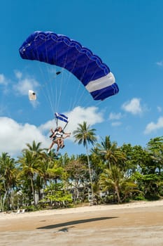Couple man woman unidentified carrying kayak into tropical waters at  mission beach nearby Cairns Queensland Australia