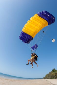 Tandem parachute teams landing on tropical mission beach sands nearby Cairns Queensland Australia