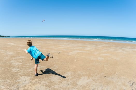 Boy throwing boomerang along tropical waters at  mission beach nearby Cairns Queensland Australia