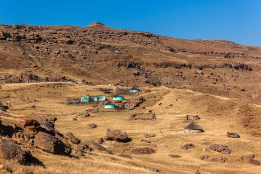 Wilderness mountains with distant habitat tribal homes on rocky mountainside terrain