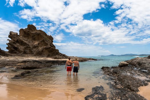 Ocean Beach blue waters and rocky headland into the scenic landscape with family in swim cove on holiday