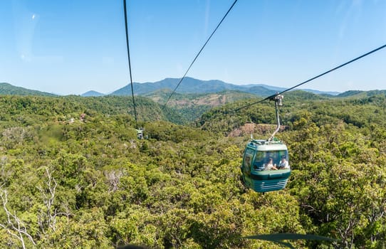 Cable car high above tropical forests with tourists admiring view of scenic landscape