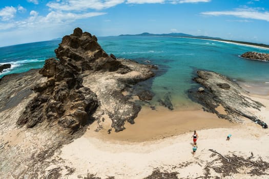 Ocean Beach blue waters and rocky headland into the scenic landscape with family in swim cove on holiday