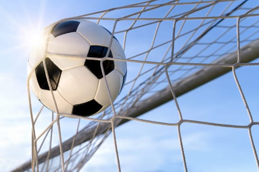 Football flies into the goal in front of blue sky,with backlight