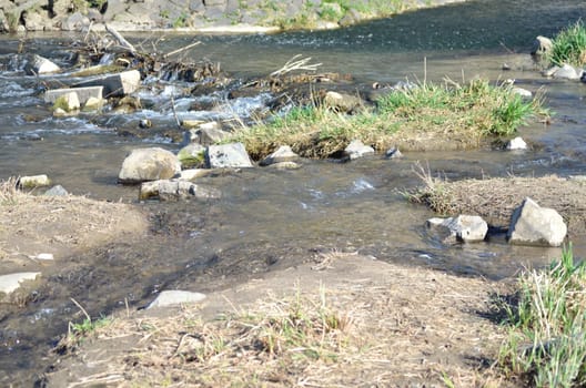 Relaxation with an idyllic view,a beautiful place on a white water - stream with small boulders,stones,grass and sand