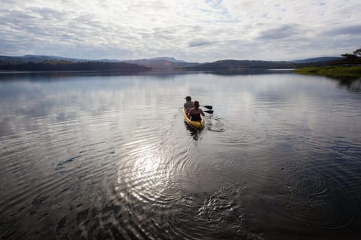 Girl boy paddle out on dam smooth waters to bass fish