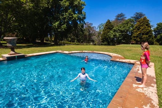Girls cousins teenagers in home swimming pool playtime outdoors summer