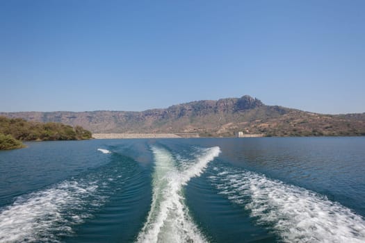 Ski boat propellor water wake behind on dam or  lake blue waters landscape