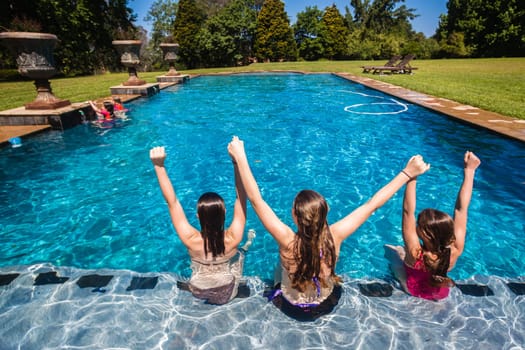 Girls cousins teenagers in home swimming pool playtime outdoors summer