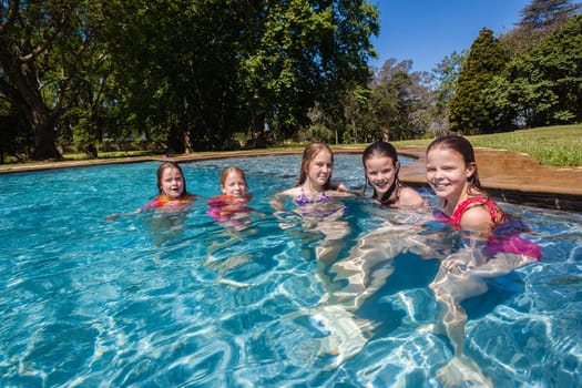 Girls cousins teenagers in home swimming pool playtime outdoors summer
