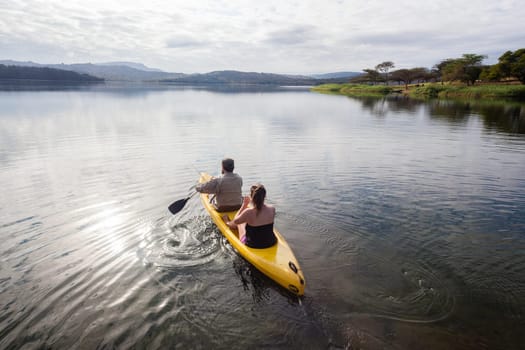 Teenage girls going out on yellow canoe to explore dam lake waters and shoreline