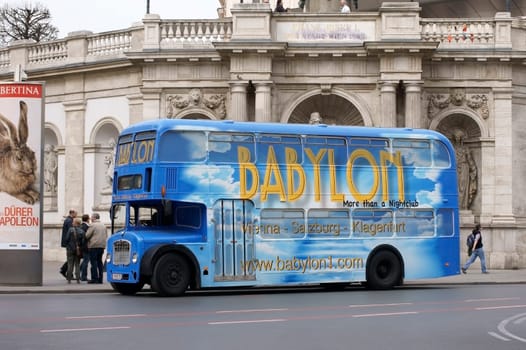 Vienna,Austria – March 31,2014: A group of tourists stands next to a double-decker bus with distinctive advertising on March 30,2014 in Vienna.