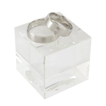 A pair of white gold rings on cubic glass isolated on white.