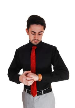 A closeup picture of a young man in a black shirt with red tie looking on his.watch, with a beard, isolated for white background..
